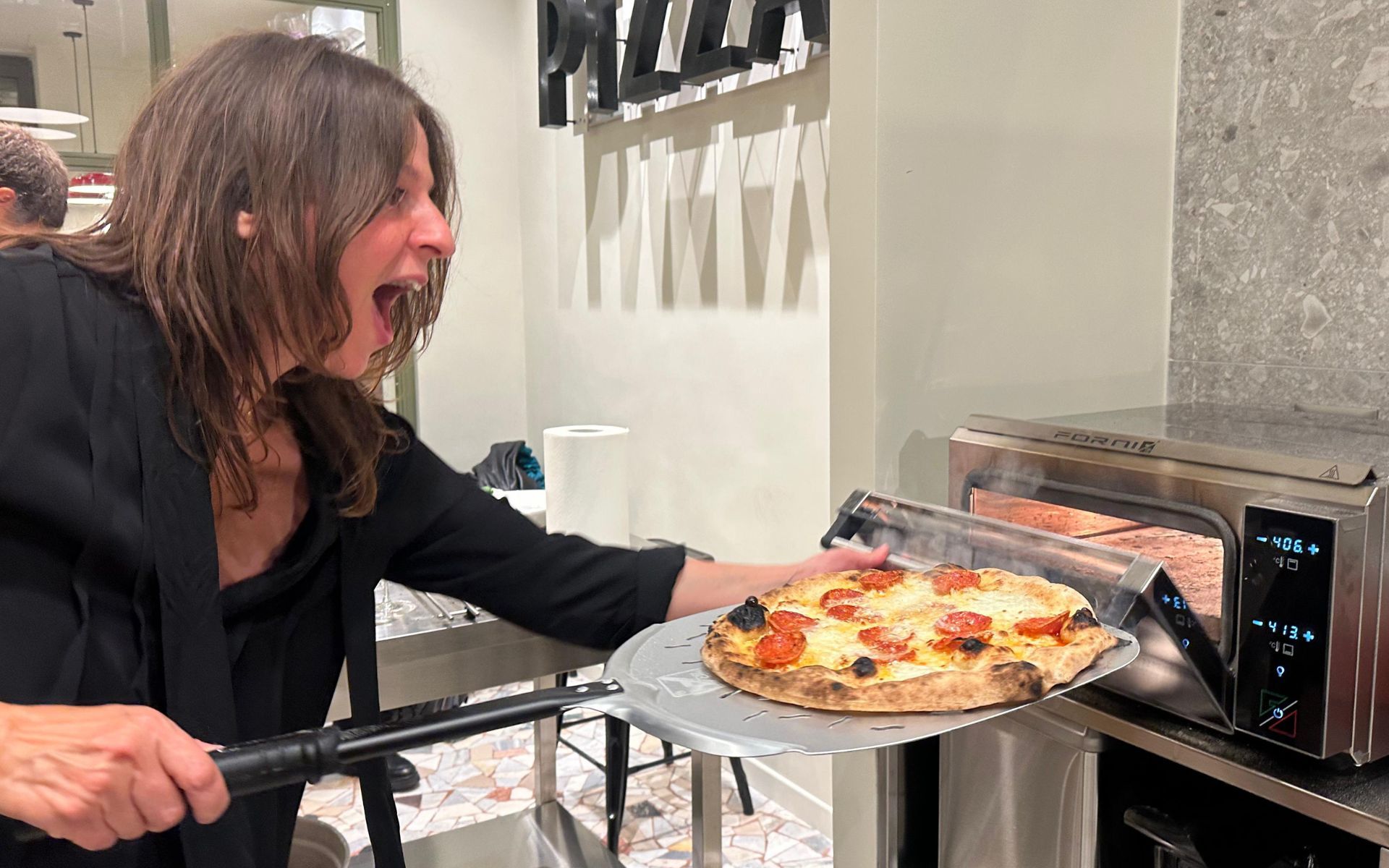 Ched putting pizza in the oven
